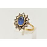 A SAPPHIRE AND DIAMOND CLUSTER RING, oval cut blue sapphire set within a yellow gold bezel mount,