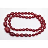 A GRADUATING BAKELITE BEAD NECKLACE, oval cherry amber colour beads, graduating in size, largest