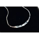 A 9CT GOLD, TOPAZ NECKLACE, a solid white gold crecent shaped bar, set with four emerald cut blue