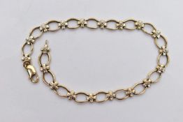 A 9CT GOLD DIAMOND BRACELET, designed with a series of oval openwork links, interspaced with cross