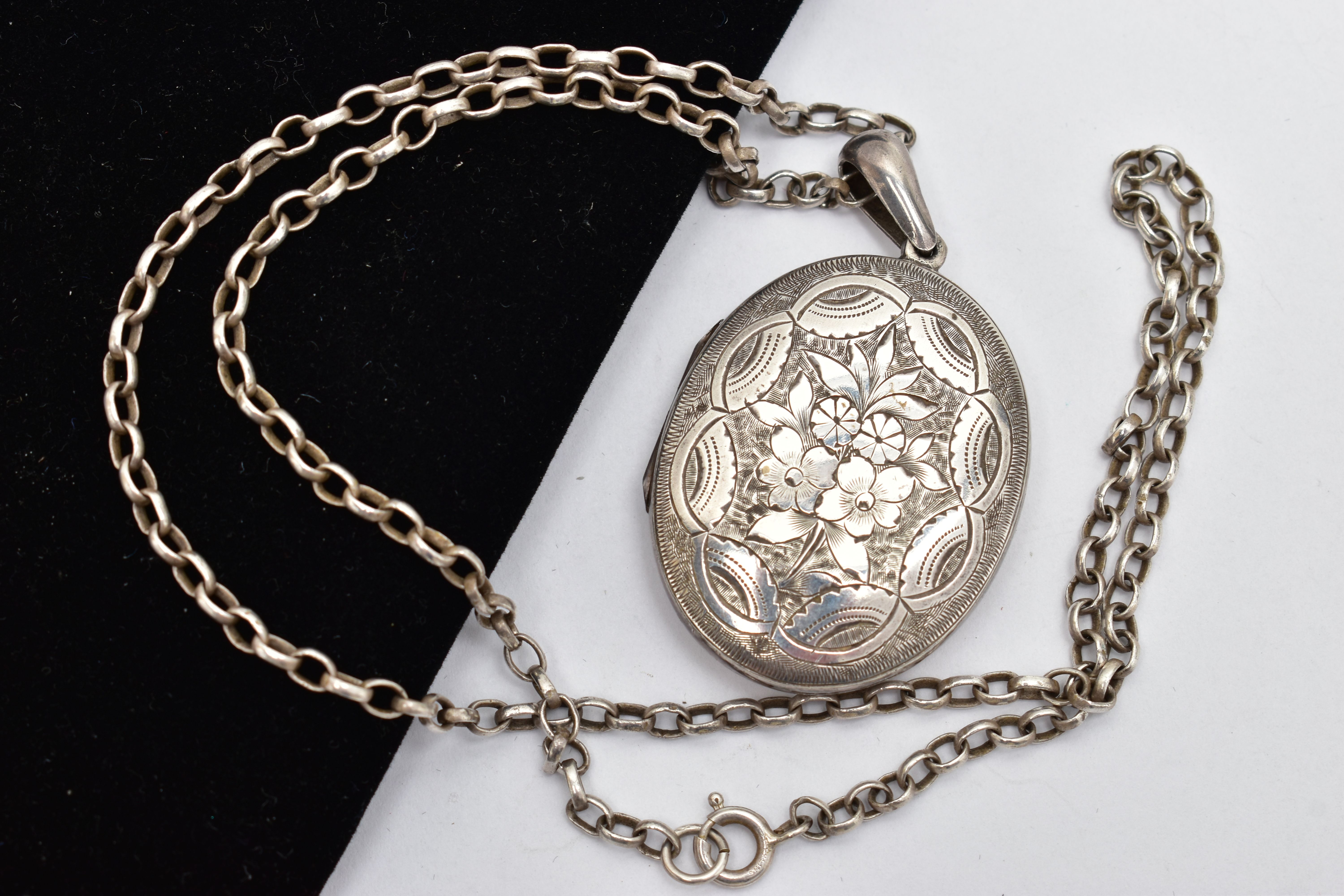 A LATE VICTORIAN SILVER LOCKET AND CHAIN, the oval locket detailed with a floral design, opens to