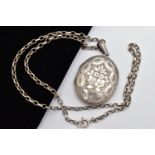 A LATE VICTORIAN SILVER LOCKET AND CHAIN, the oval locket detailed with a floral design, opens to