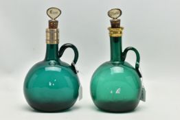 TWO VICTORIAN GREEN GLASS DECANTERS WITH METAL MOUNTS AND LOOP HANDLES, both with an ill-fitting