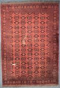 A 20TH CENTURY RED RUG, with a repeating pattern, and multi strap border, 294cm x 203cm (