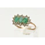 A 9CT GOLD, EMERALD AND DIAMOND CLUSTER RING, designed with three claw set, oval cut emeralds, in