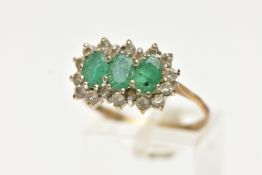 A 9CT GOLD, EMERALD AND DIAMOND CLUSTER RING, designed with three claw set, oval cut emeralds, in