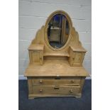 A PINE DRESSING TABLE, with two panelled cupboards flanking an oval bevelled edge swing mirror, on a