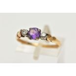 A YELLOW METAL AMETHYST AND DIAMOND RING, centring on a claw set, circular cut amethyst, flanked