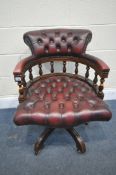 A BURGUNDY LEATHER BUTTONED SWIVEL OFFICE CHAIR, with spindled armrests, on five shaped legs,