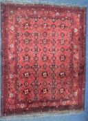 A LATE 19TH/EARLY 20TH CENTURY RUG, red field within a repeating geometric pattern, and multi