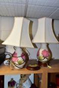 A PAIR OF MOORCROFT POTTERY TABLE LAMPS, comprising two pink magnolia on cream ground lamp bases