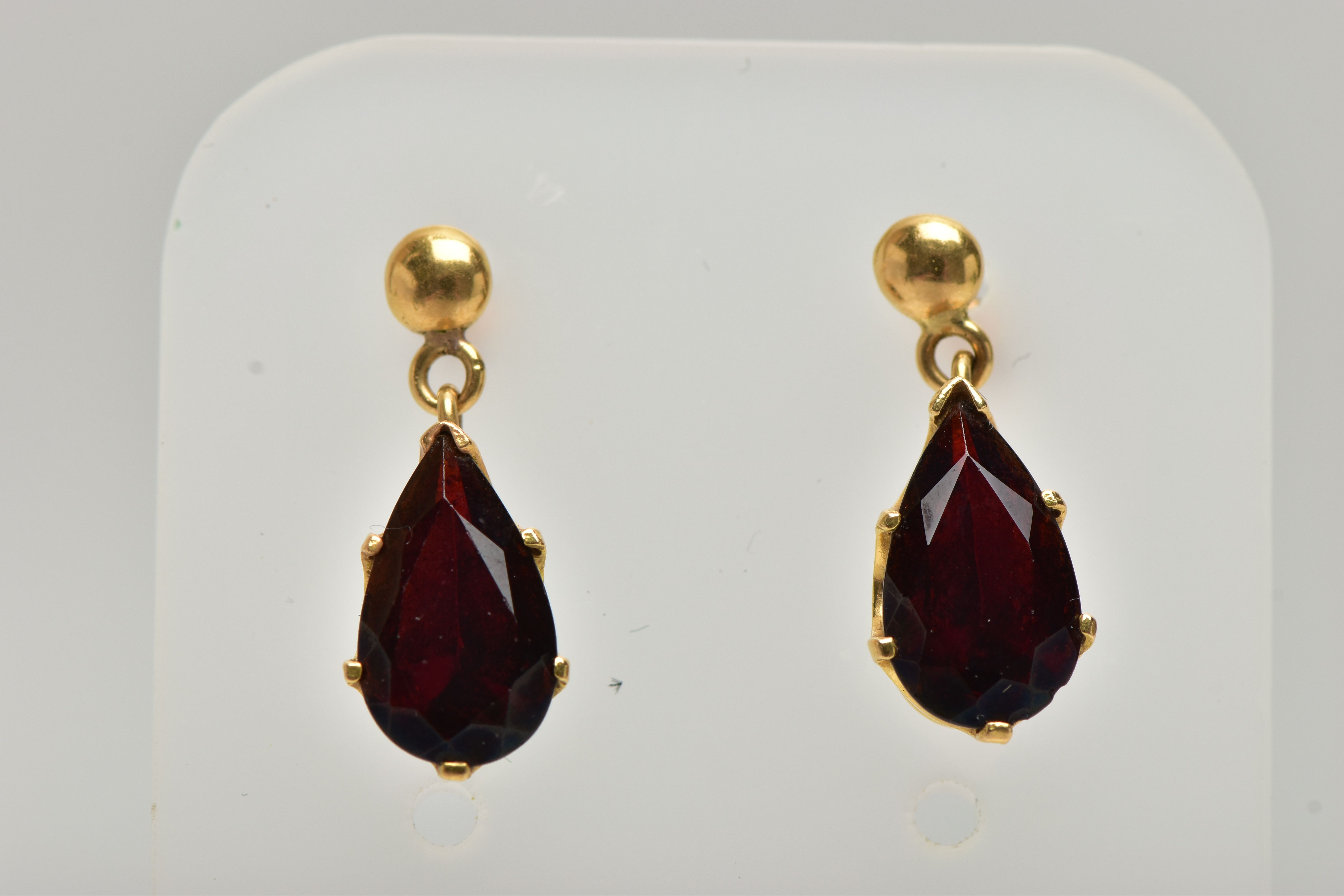 A PAIR OF GARNET DROP EARRINGS, each set with a pear cut garnet drop, claw set into a yellow gold