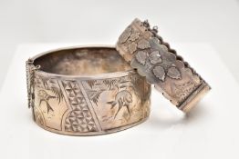 TWO LATE VICTORIAN SILVER BANGLES, the first a wide hinged bangle, decorated with engraved birds and