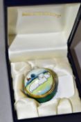 A BOXED MOORCROFT ENAMELS PILL BOX, of circular form, decorated with sheep in a rural landscape,