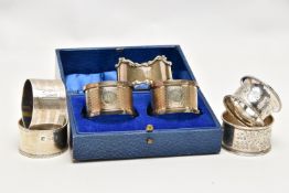 A PAIR OF CASED GEORGE V SILVER CIRCULAR NAPKIN RINGS AND FIVE OTHER SILVER NAPKIN RINGS, the