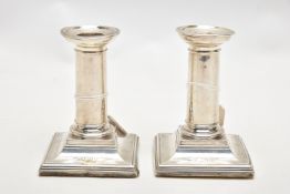 A PAIR OF LATE VICTORIAN SILVER CANDLESTICKS, polished columns, on weighted square bases, engraved