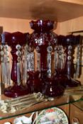THREE CRANBERRY GLASS LUSTRES, VASES AND SPARE LUSTRE DROPS, comprising a single cranberry glass