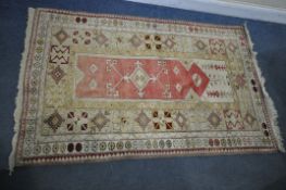 A PERSIAN MILAS RUG, cream and gold, and central red field, 190cm x 120cm (discolouration) and a