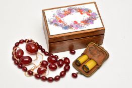 A SMALL WOODEN BOX WITH BAKELITE BEADS AND TWO CHEROOTS, the small wooden box with a painted