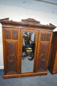 AN EDWARDIAN WALNUT TRIPLE DOOR COMPACTUM WARDROBE, with an overhanging cornice with foliate carving