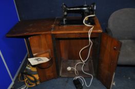A VINTAGE SINGER SEWING MACHINE CABINET with electric Singer sewing machine fitted (PAT fail due