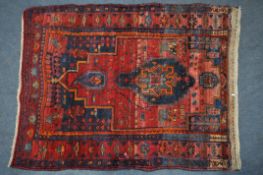 A 20TH CENTURY IRANIAN PATTERENED RED GROUND RUG, 175cm x 135cm