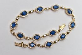 A YELLOW METAL GEM SET BRACELET, comprised of twelve oval cut synthetic blue spinel, each set with a