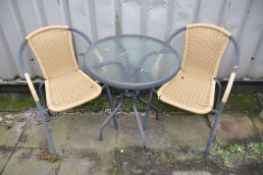 A CIRCULAR METAL GARDEN TABLE with glass top along with two rattan style chairs (3)