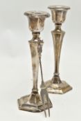 A PAIR OF SILVER CANDLESTICKS AND A TWO PRONG FORK, the candlesticks of a tapered hexagonal form, on