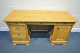 A SOLID LIGHT OAK DESK, with an arrangement of six soft open and close drawers and a single cupboard