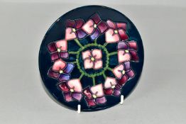 A MOORCROFT POTTERY PLATE DECORATED WITH A VIOLETS PATTERN, dark blue ground, impressed and