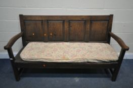 A GEORGIAN OAK HALL SETTLE, with four fielded panels to the back, open armrests, on a slatted