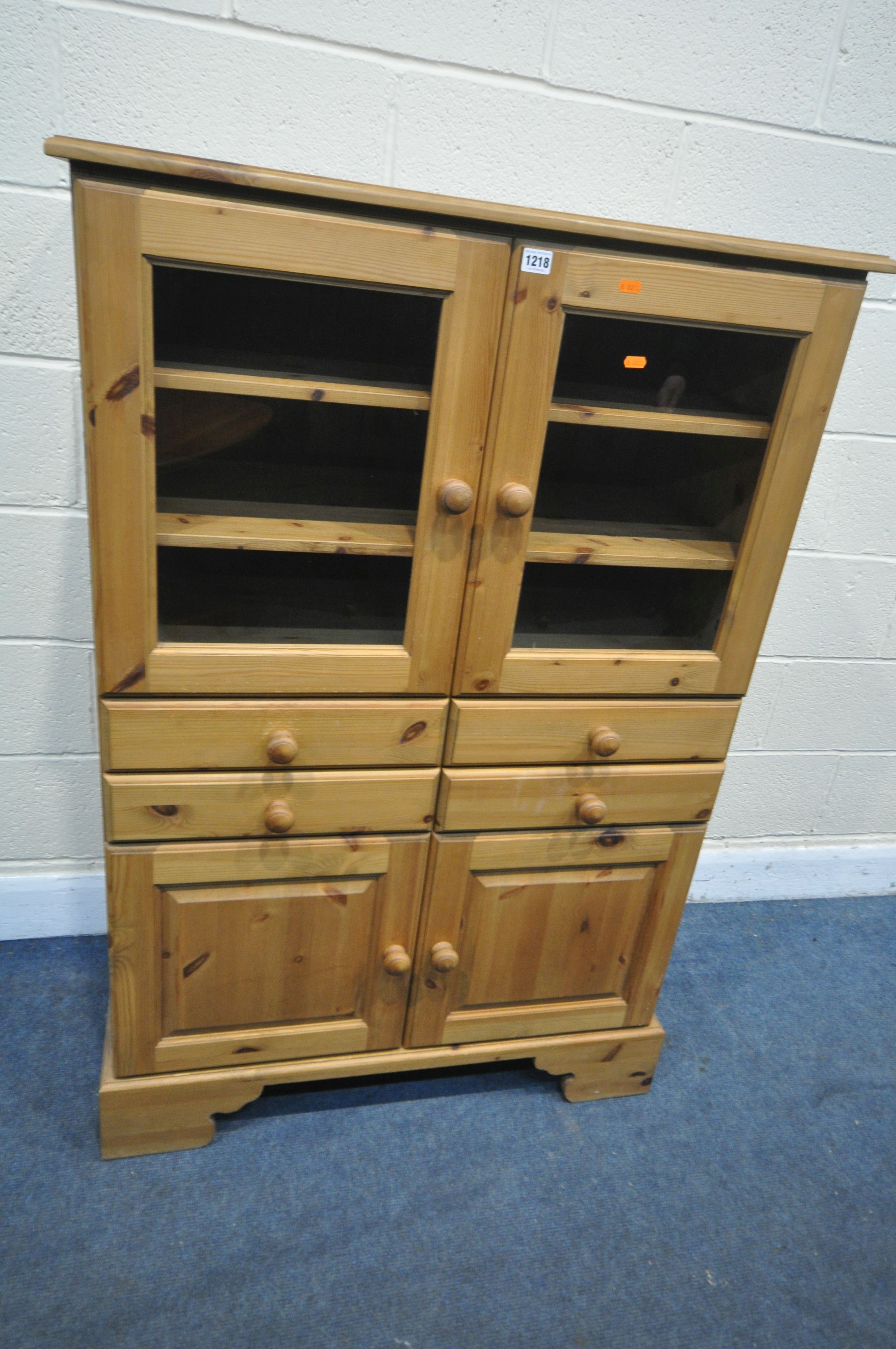 A PINE CABINET, with two glazed doors, enclosing two loose shelves, above four drawers, and two