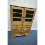A PINE CABINET, with two glazed doors, enclosing two loose shelves, above four drawers, and two
