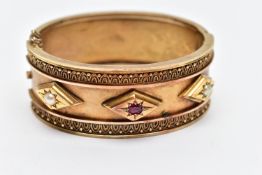 A LATE VICTORIAN GEM SET HINGED BANGLE CIRCA 1890, set with a cushion shape ruby and two split