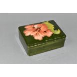 A MOORCROFT POTTERY RECTANGULAR TRINKET BOX AND COVER DECORATED IN A CORAL HIBISCUS PATTERN, on a