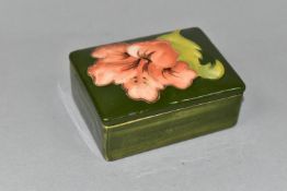 A MOORCROFT POTTERY RECTANGULAR TRINKET BOX AND COVER DECORATED IN A CORAL HIBISCUS PATTERN, on a