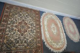 A DARK PINK AND FLORAL OVAL CHINESE RUG, 150cm x 93cm, a smaller pink oval rug, and another rug (