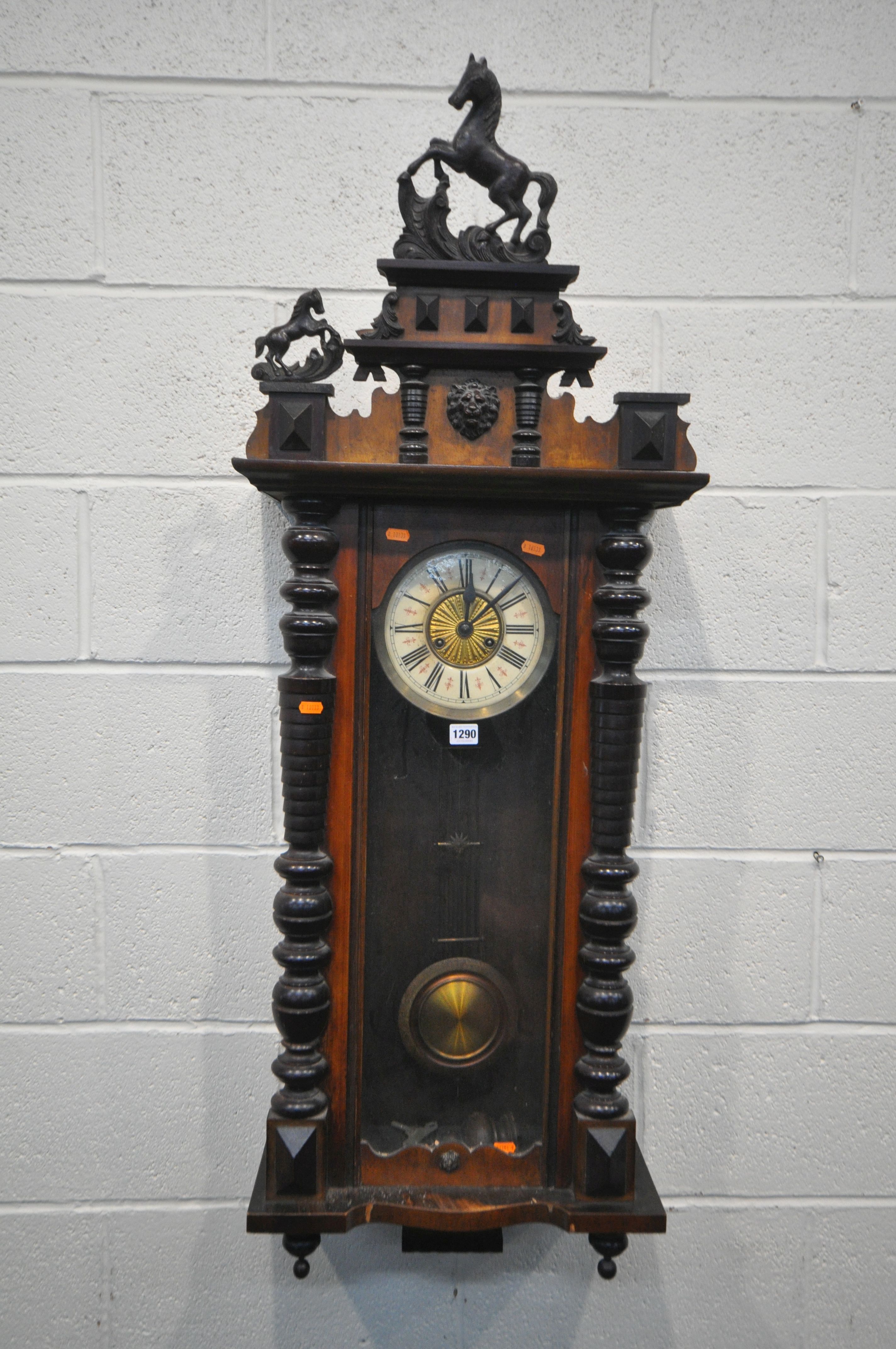 A LATE 19TH CENTURY WALNUT VIENNA WALL CLOCK, with two carved horse pediments, enamel dial with