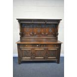 A 20TH CENTURY SOLID OAK DRESSER, the top with a fixed overhanging cornice, and three carved panels,