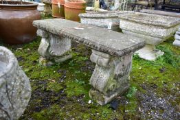 A WEATHERED COMPOSITE GARDEN BENCH, on a twin scrolled base, length 97cm x depth 37cm x height