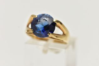 A YELLOW METAL GEM SET RING, a circular cut synthetic blue sapphire, in a four prong setting,