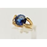 A YELLOW METAL GEM SET RING, a circular cut synthetic blue sapphire, in a four prong setting,