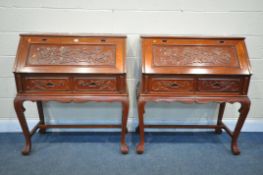 A PAIR OF ORIENTAL CARVED HARDWOOD BUREAU'S, the fall front enclosing a fitted interior, above two
