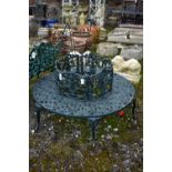 A CAST ALUMINIUM ROUND TREE BENCH, decorated with still life flowers to the backrest, scrolls to the