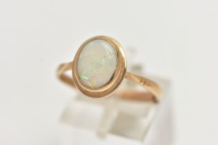 A 9CT GOLD OPAL RING, designed with an oval opal cabochon, collet set to the yellow gold rim,