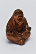 A CARVED NETSUKE FIGURE, in the form of a seated robed elder, drill holes to the back, approximate