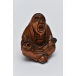 A CARVED NETSUKE FIGURE, in the form of a seated robed elder, drill holes to the back, approximate