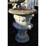 A WEATHERED COMPOSITE CAMPAGNA GARDEN URN, depicting grapes and fruiting vine, and four male