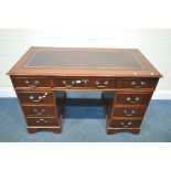 A MAHOGANY PEDESTAL DESK, with a brown leather writing surface, and an arrangement of nine